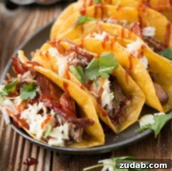 Quick & Easy BBQ Pulled Pork Pizza 5 Four BBQ Pulled Pork Tacos with yummy cheese, barbecue and cilantro on a black serving plate on a wooden table.