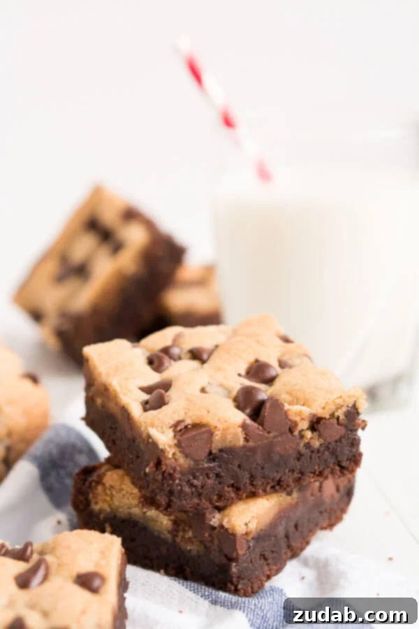 Delicious cookie brownie bars displayed on a striped towel next to a glass of cold milk, ready to be enjoyed.
