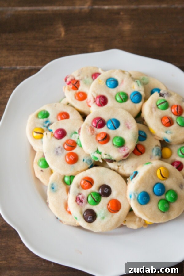 Buttery Shortbread M&M Cookies: A delightful treat for school lunches, picnics, or relaxing Sundays. A close-up of the shortbread cookie dough being rolled out with M&M candies mixed in.