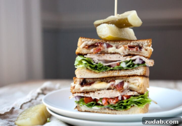 A golden-brown, crispy Grilled Cheese Club Sandwich, cut in half to reveal layers of melted cheese and fillings.