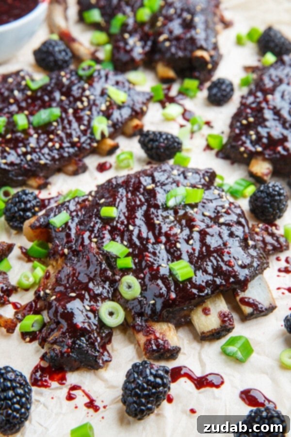 Fall-off-the-bone Blackberry Hoisin BBQ Ribs, coated in a rich, glossy sauce and garnished with fresh blackberries.