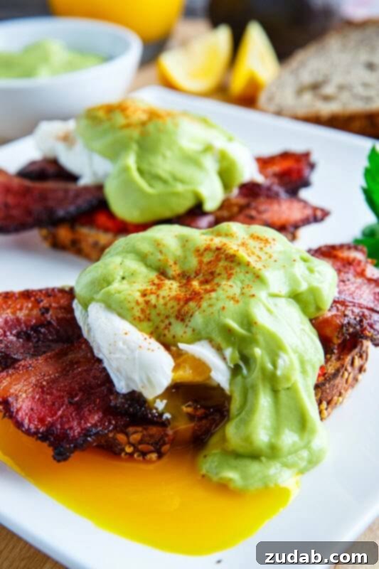 Classic Eggs Benedict featuring crispy bacon, perfectly poached eggs, and a vibrant avocado hollandaise sauce.