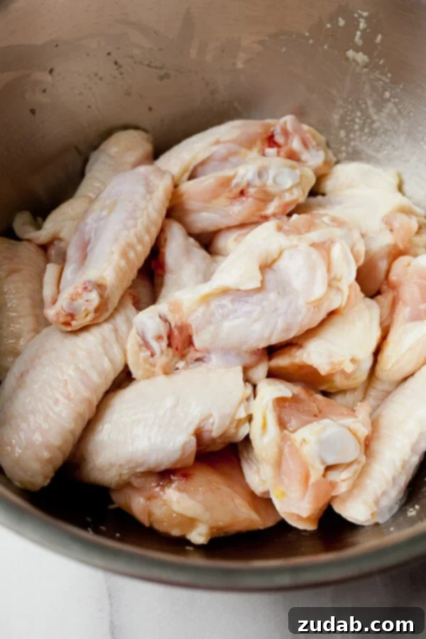 Irresistible Garlic Parmesan Grilled Wings 2 raw chicken wings in bowl being prepped to make garlic parmesan chicken wings