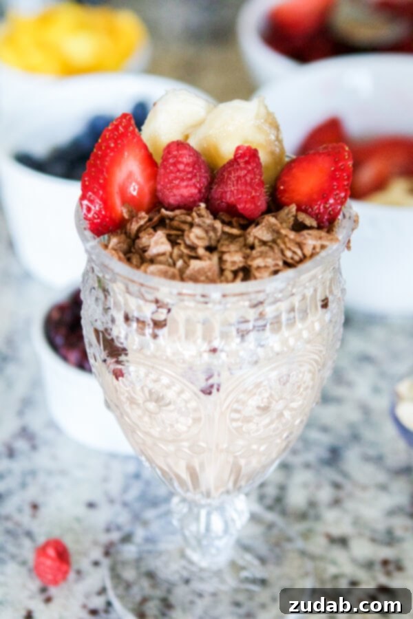 The final delicious Cinnamon Berry Crisp Yogurt Parfait, topped with whipped cream and a sprinkle of cinnamon cereal, ready to be enjoyed.