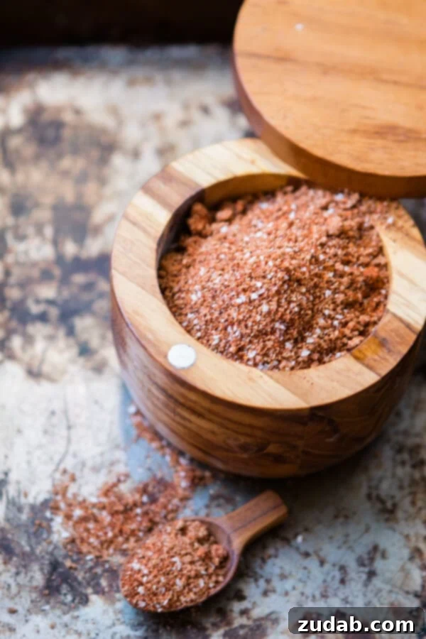 Perfect for beef, chicken and especially pork, this smoky bbq rub is what makes grilling so amazingly delicious. Just dig in! Homemade BBQ dry rub in a rustic wooden container next to a small wooden scoop, ready for grilling.