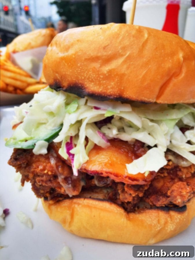 Tilt Portland Mother Clucker Sandwich A close-up of Tilt's famous 'Mother Clucker' fried chicken sandwich, topped with bacon and coleslaw.