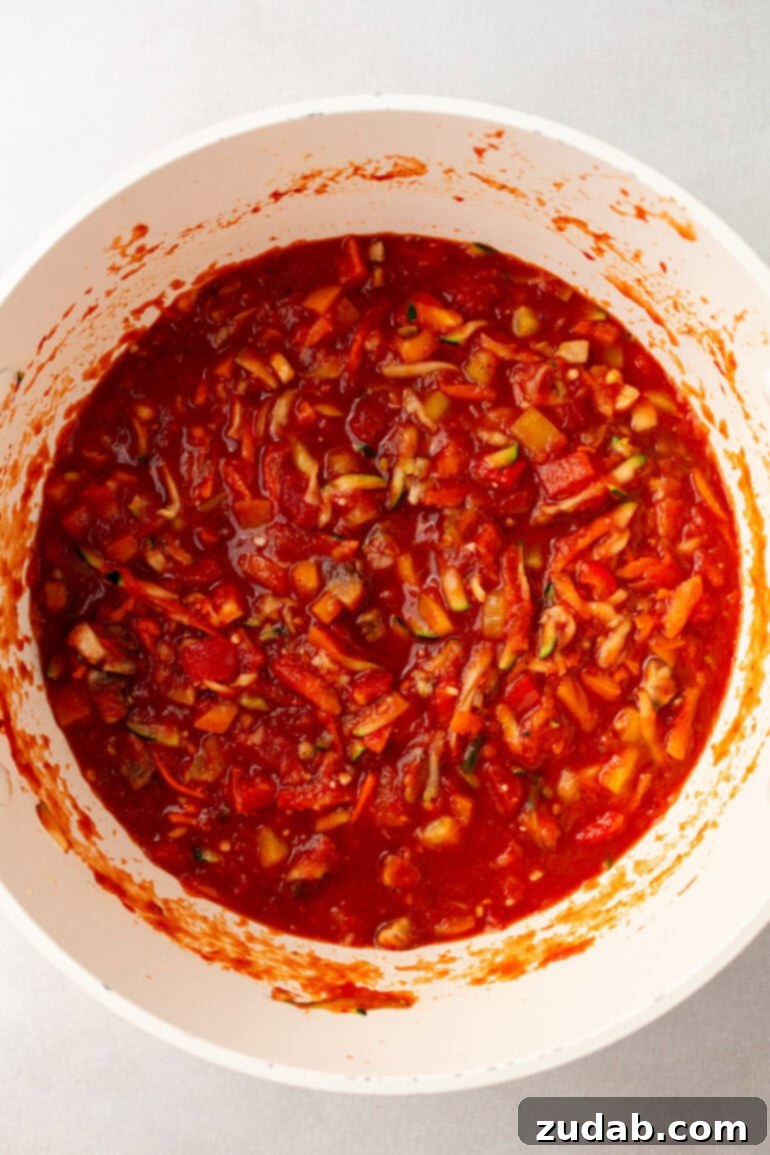 Garden-Fresh Homemade Marinara Sauce 7 A Dutch oven filled with rich, red vegetable marinara sauce, gently simmering on the stovetop, releasing fragrant steam.