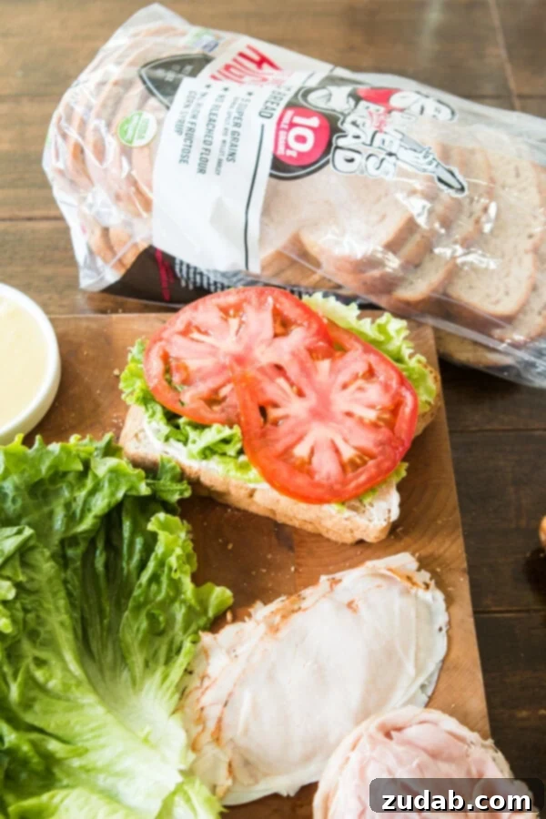 The Ultimate Triple Decker Club Sandwich 6 a photo of a club sandwich being assembled with a bag of Dave's Killer Bread sitting next to the sandwich.