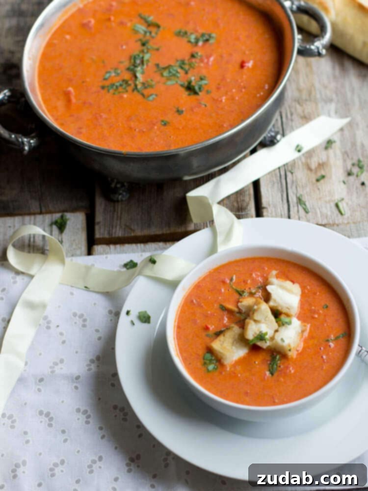 A rustic bowl of vibrant Roasted Tomato Basil Soup, garnished with fresh basil leaves, highlighting the rich red color from roasted tomatoes.