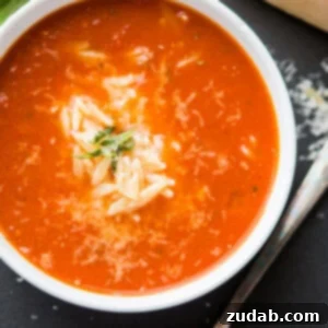 A vibrant bowl of Zupas Copycat Tomato Basil Orzo Soup, showcasing the creamy texture and fresh basil topping, ready to be enjoyed.