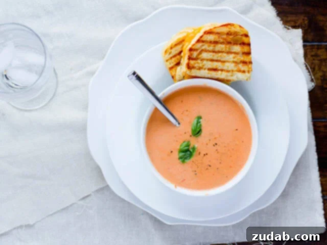 A classic comfort food pairing: creamy Cream of Tomato Soup with a perfectly grilled three-cheese sandwich, golden and inviting.