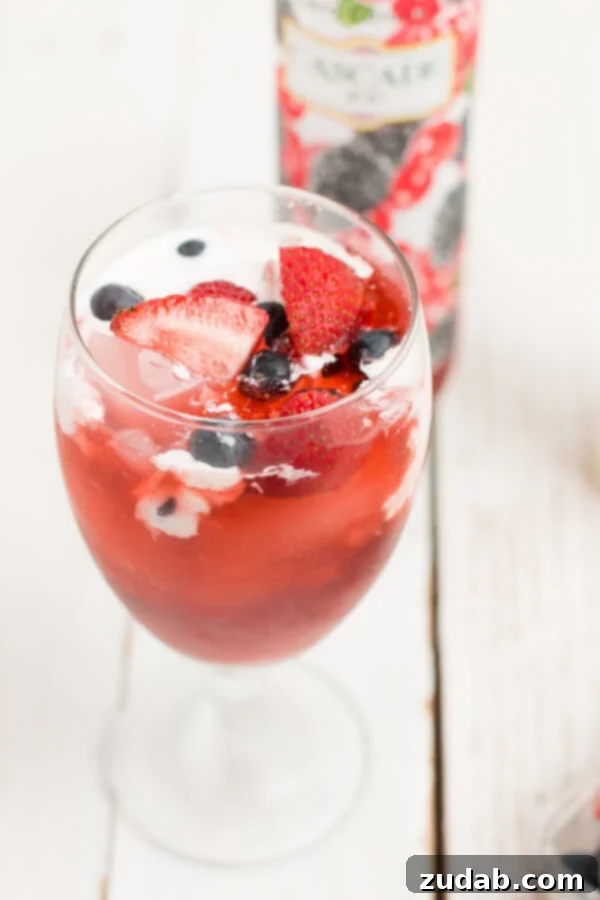 Classic Italian Soda A clear glass filled with a colorful Italian soda, layered with fruit syrup, sparkling water, and cream, a classic customizable refreshment.