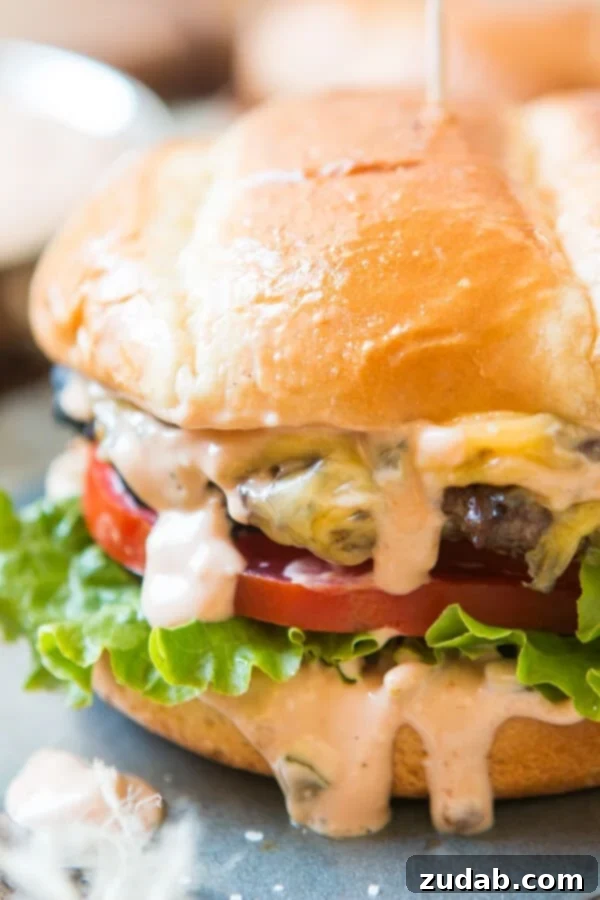 Elevate Your Burger with the Best Homemade Killer Burger Sauce Recipe A perfectly assembled cheeseburger showcasing a rich, homemade killer burger sauce generously dripping down its sides, accompanied by fresh lettuce and a juicy tomato slice.