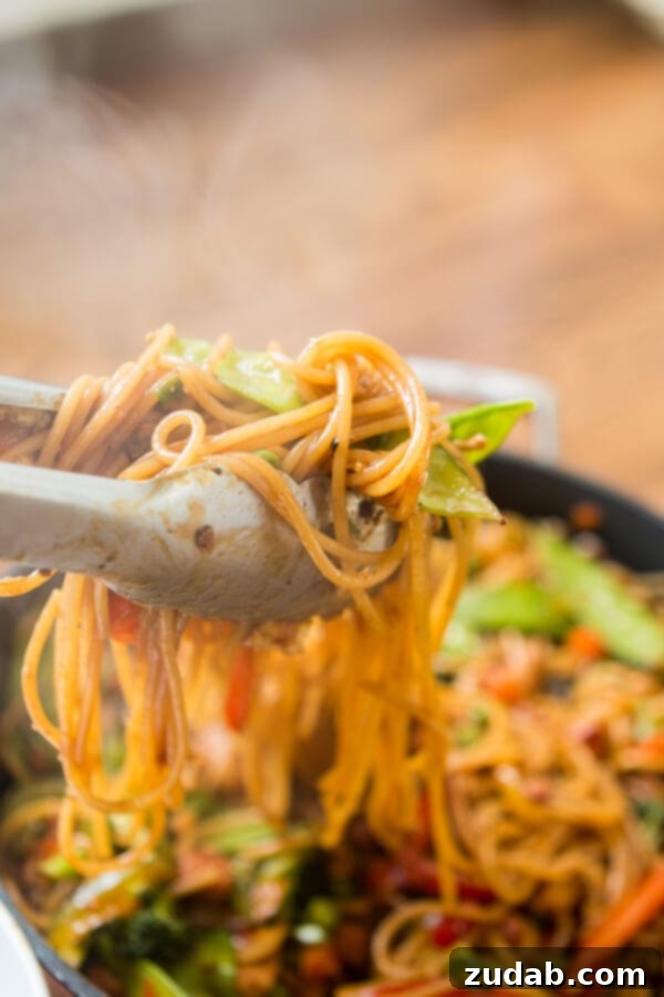 Teriyaki Chicken Noodles: Flavorful and Easy Weeknight Meal A serving of Teriyaki Chicken Noodles with a fork, emphasizing the readiness to eat.
