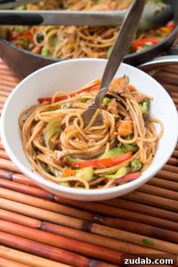 Tossing Noodles with Teriyaki Sauce and Vegetables Cooked noodles being tossed with the homemade teriyaki sauce and vegetables in a large skillet.