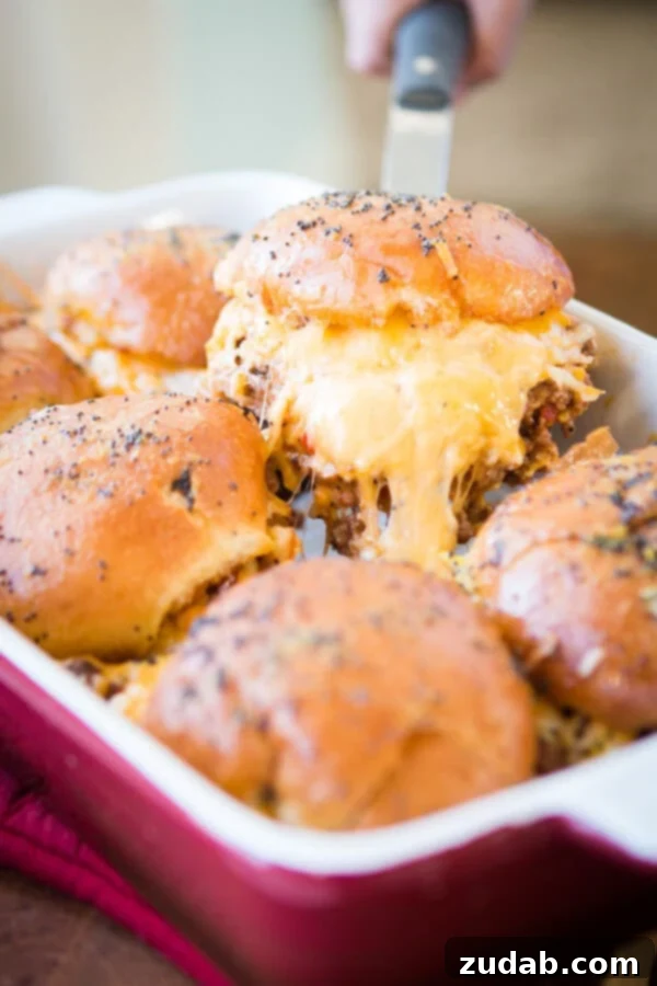 Saucy and Cheesy Sloppy Joe Sliders, a new twist on a classic. Batch of Cheesy Sloppy Joe Sliders baked to perfection in a baking dish.