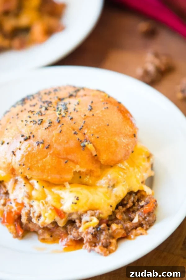 Deliciously Saucy and Cheesy Sloppy Joe Sliders Close-up of golden brown Cheesy Sloppy Joe Sliders with melted cheese peeking out.