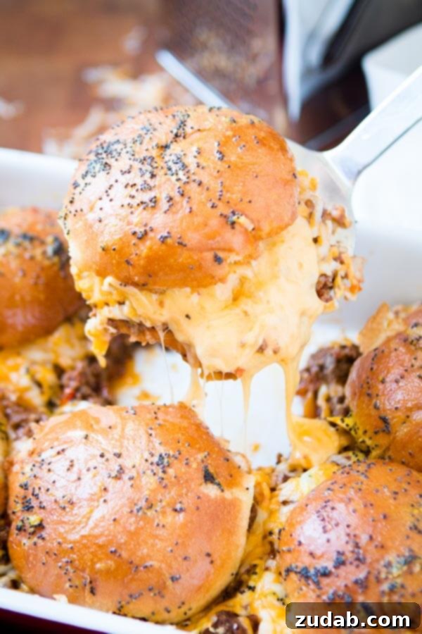 Serving up Cheesy Sloppy Joe Sliders A spatula carefully lifting a single Cheesy Sloppy Joe Slider from the pan.