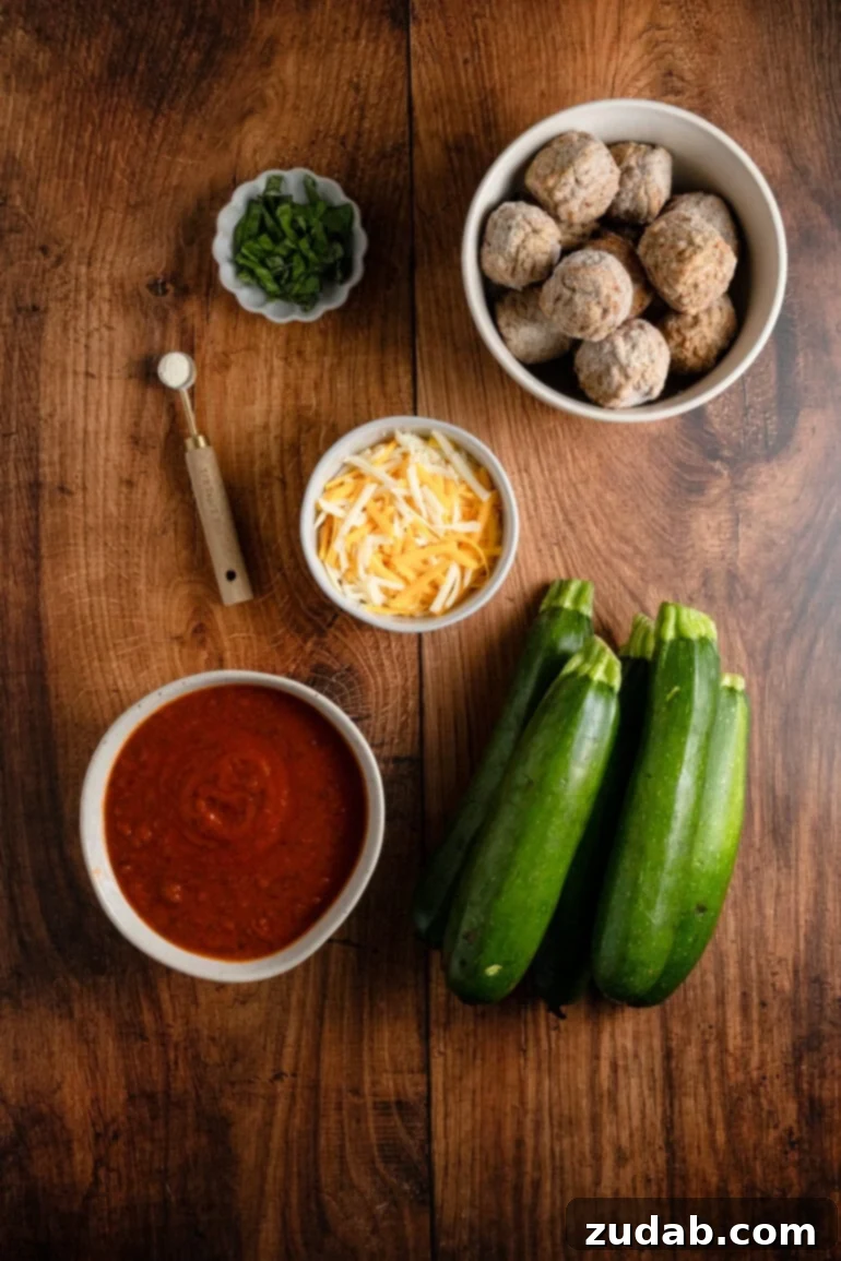Individual bowls brimming with fresh marinara sauce, shredded cheese blend, frozen turkey meatballs, and fragrant basil, neatly arranged alongside whole zucchinis and a sprinkle of salt, showcasing all the ingredients for the skillet dish.