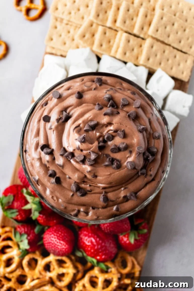 Decadent Brownie Batter Dip 9 A vibrant display of brownie batter dip, surrounded by an assortment of dippers including pretzels, fresh strawberries, graham crackers, and fluffy marshmallows.