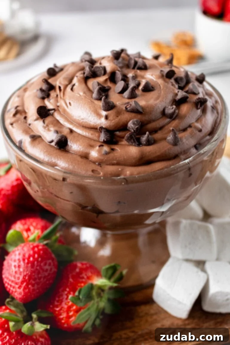 Decadent Brownie Batter Dip 10 A glass bowl of creamy chocolate brownie dip, beautifully surrounded by whole strawberries and large marshmallows, ready for dipping.