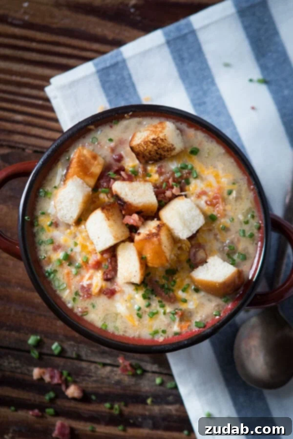 A close-up shot of creamy cheeseburger soup topped with crunchy golden croutons and delicate chives in a rustic bowl.