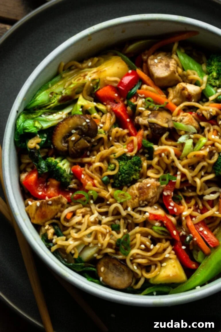 Lightning-Fast 15-Minute Chicken Stir-Fry 2 A large bowl filled with yakisoba noodles and colorful stir-fried vegetables, including red peppers, mushrooms, chicken chunks, and baby bok choy, ready to be enjoyed.