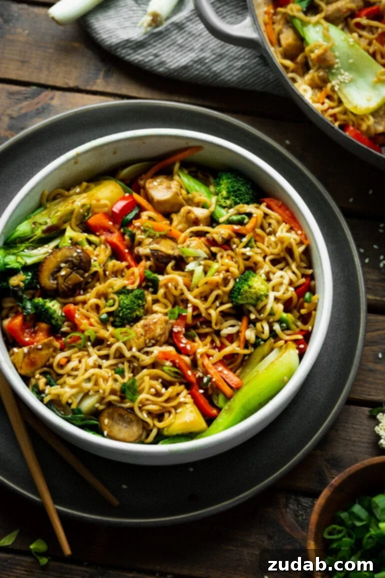 Lightning-Fast 15-Minute Chicken Stir-Fry 3 A mouth-watering bowl of chicken stir fry with yakisoba noodles, garnished with green onions and sesame seeds, with chopsticks resting beside it, inviting a quick and easy meal.