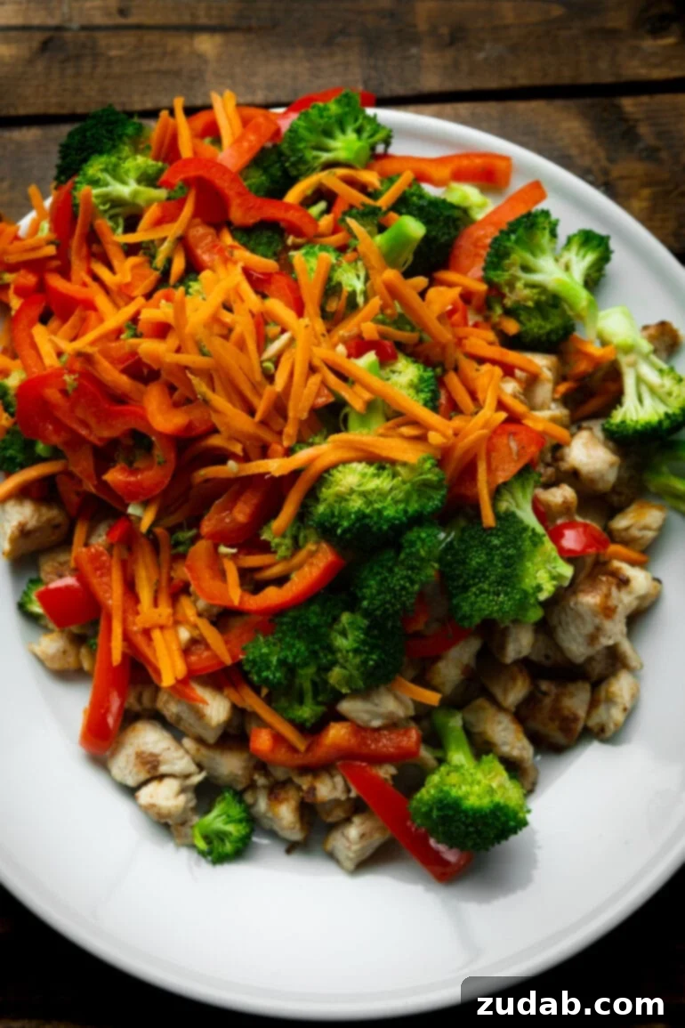 Lightning-Fast 15-Minute Chicken Stir-Fry 4 A vibrant display of fresh ingredients for chicken stir fry, including crisp broccoli, finely shredded matchstick carrots, bright red bell peppers, and tender chicken pieces, laid out on a wooden board.