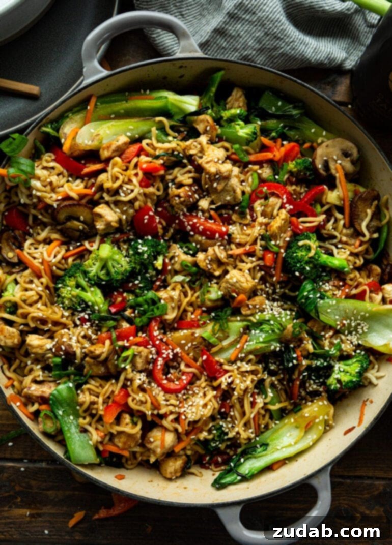 Lightning-Fast 15-Minute Chicken Stir-Fry 6 A large, steaming Dutch oven is brimming with an Asian noodle dish, generously mixed with tender broccoli, earthy mushrooms, vibrant red bell peppers, and succulent chicken pieces, all coated in a rich sauce.