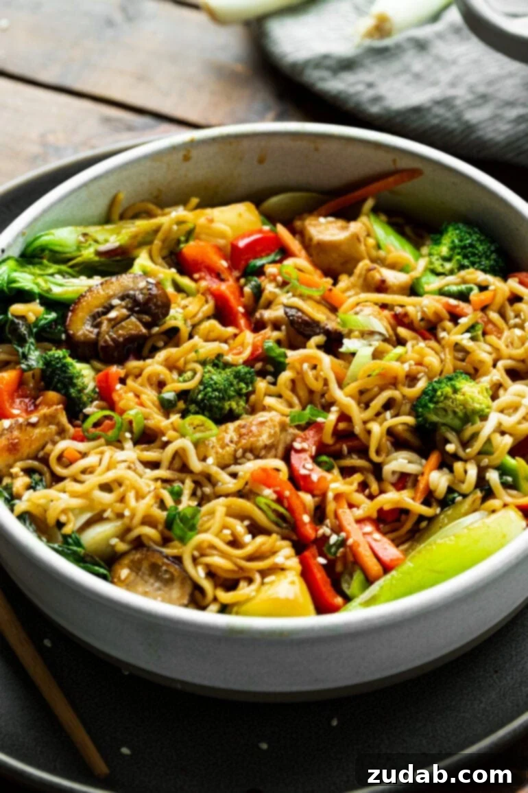 Lightning-Fast 15-Minute Chicken Stir-Fry 7 A beautifully presented bowl of an Asian noodle dish, generously filled with crisp vegetables, tender chicken, and springy noodles, all coated in a savory sauce, ready to be devoured.