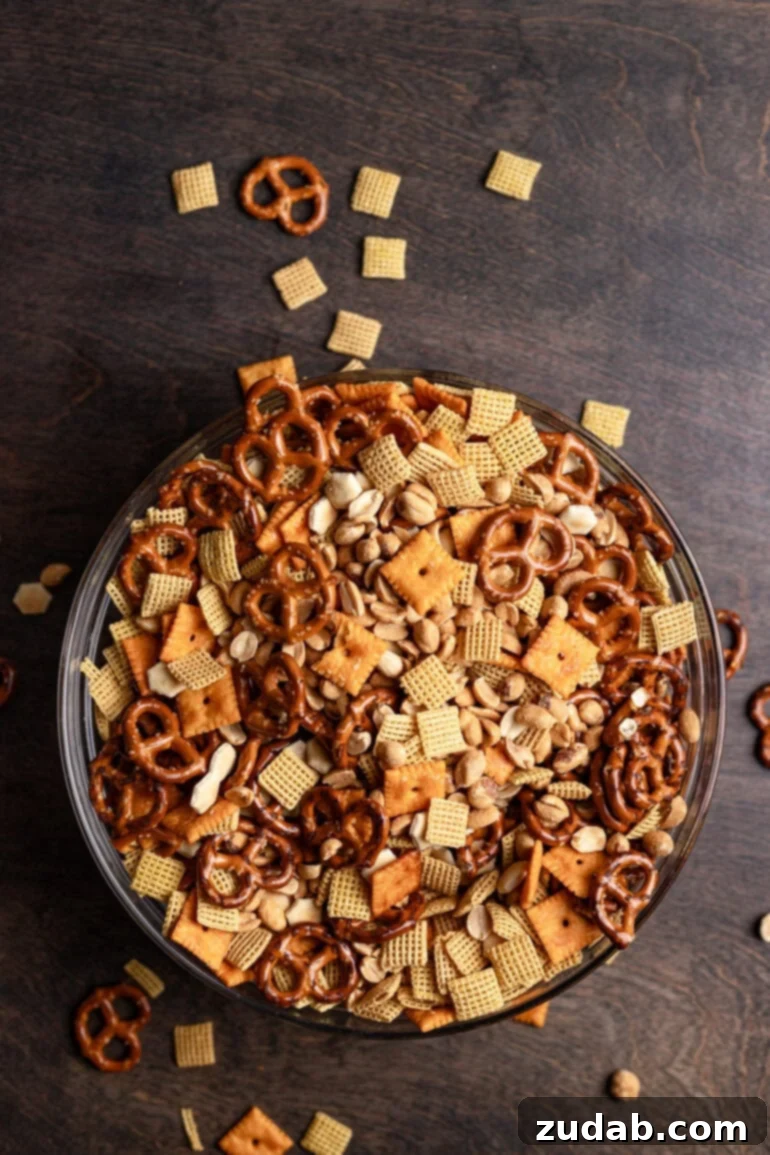 Whip Up Easy Ranch Chex Mix in Your Slow Cooker 7 A large, inviting glass bowl brimming with homemade ranch Chex mix, featuring an appetizing blend of crispy Chex cereal, crunchy Cheez-Its, salty pretzels, and savory oyster crackers. This savory snack is ready to be enjoyed!