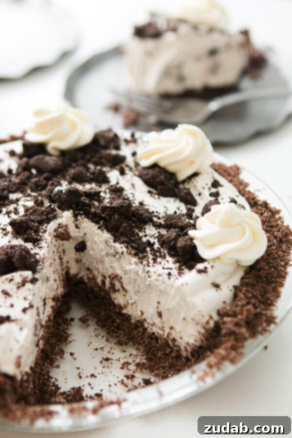 This is one of our most popular pie recipes and it's an easy pie recipe! Who wants a slice of no bake oreo pie with chocolate graham cracker crust?! a no bake oreo pie with a slice missing