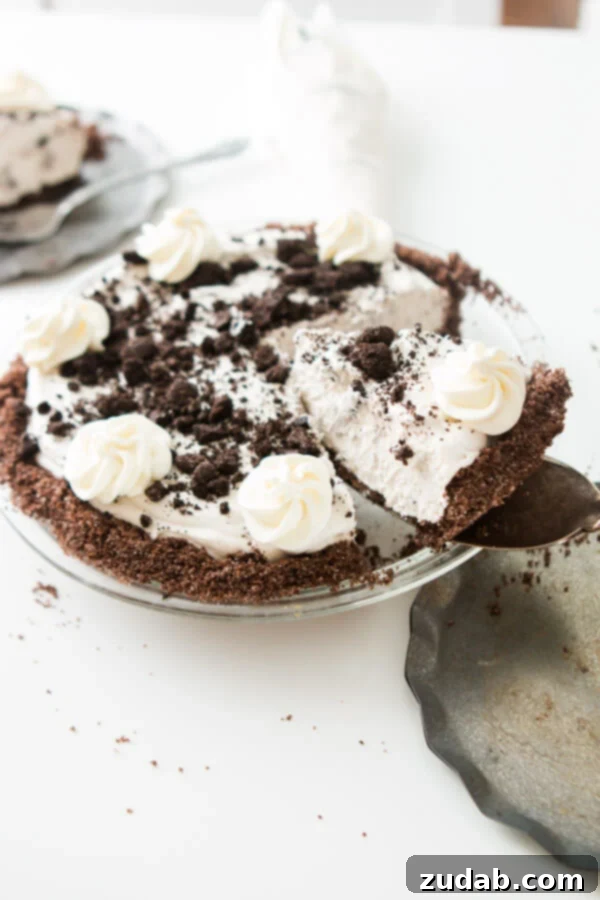 This is one of our most popular pie recipes and it's an easy pie recipe! Who wants a slice of no bake oreo pie with chocolate graham cracker crust?! Scooping out a slice of homemade no bake oreo pie with chocolate graham cracker crust.