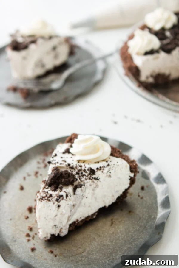 This is one of our most popular pie recipes and it's an easy pie recipe! Who wants a slice of no bake oreo pie with chocolate graham cracker crust?! A slice of no bake oreo pie with chocolate graham cracker crust on a silver serving plate.
