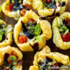 Speedy Cheesy Caprese Pesto Tarts 12 A beautiful plate of golden Caprese pesto tarts, garnished with balsamic glaze, fresh basil leaves, and vibrant grape tomatoes.