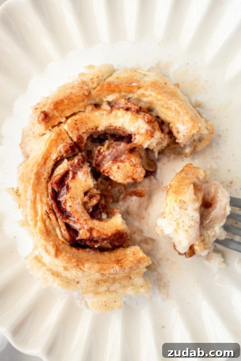 Rustic Orchard Apple Swirls 10 A delicious heirloom apple roll with a bite taken out, showcasing its flaky pastry, warm spices, and tender apple filling.