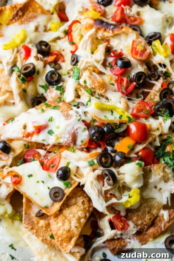 How to Make Italian Nachos 5 A close up of Italian Nachos with olives, chicken, cheese, alfredo and peppers!