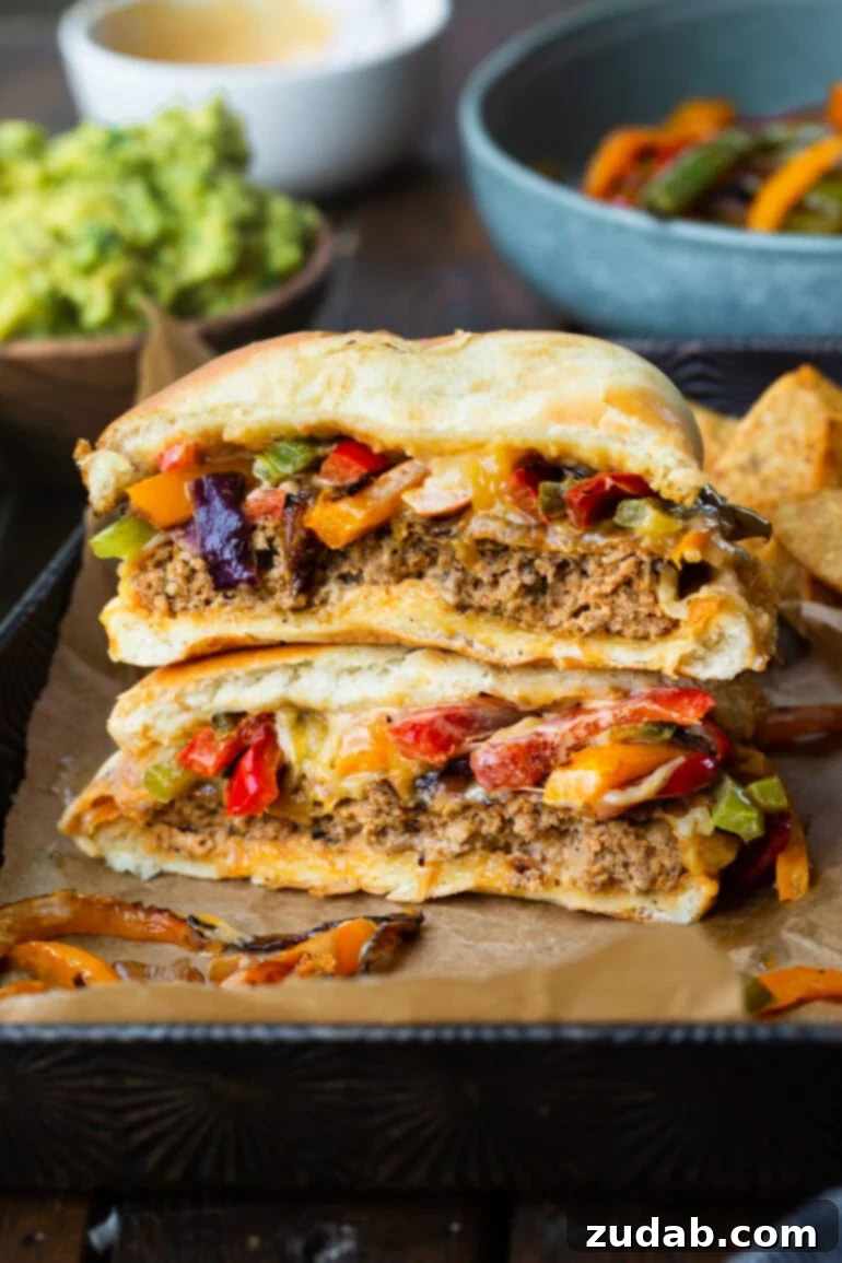 A vibrant fajita style Mexican turkey burger, cut in half to reveal its juicy interior, stacked with sautéed onions and peppers, ready to be enjoyed.