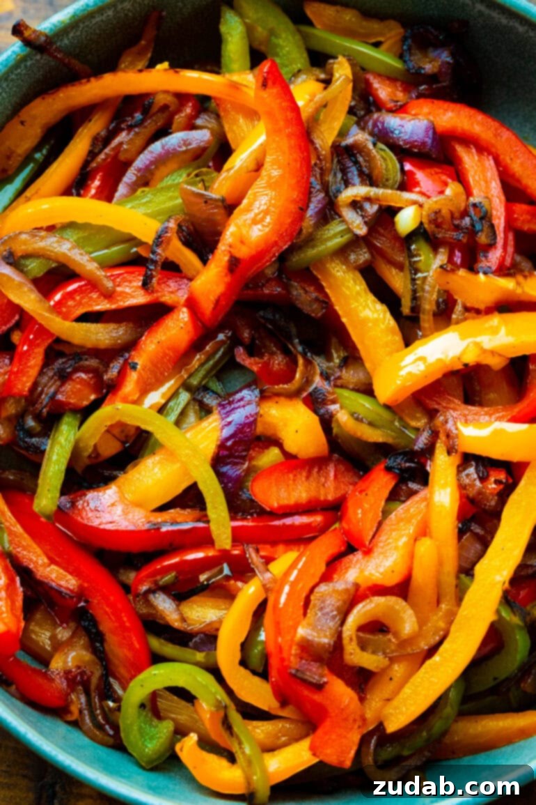 A close-up shot of colorful, tender sautéed onions and bell peppers, perfectly caramelized and ready to top the fajita burgers.
