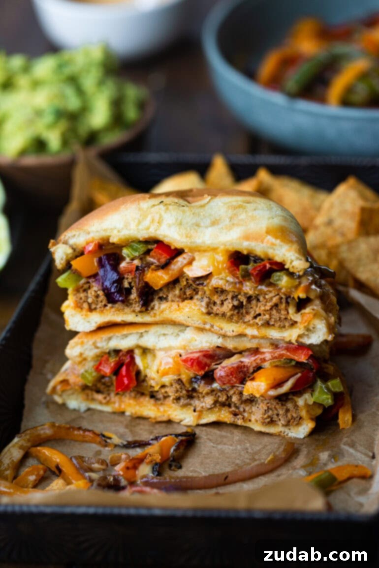 Two halves of a fajita turkey burger, stacked to showcase the juicy patty, melted cheese, and colorful sautéed peppers and onions, a perfect bite.