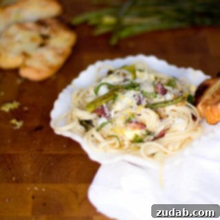 A close-up of a serving of Lemon Asparagus Pasta with hard-boiled eggs and crispy speck.