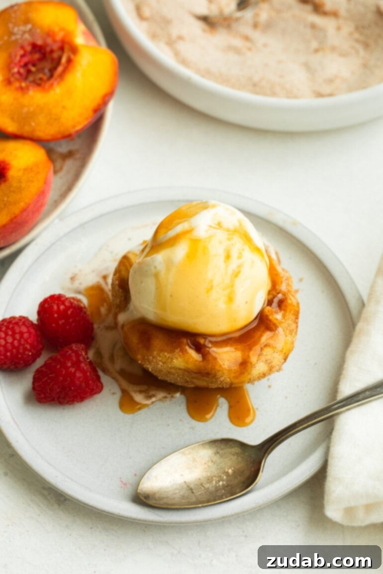 Deep Fried Peaches and Ice Cream ohsweetbasil.com A bowl of deep-fried peaches with vanilla ice cream and fresh raspberries
