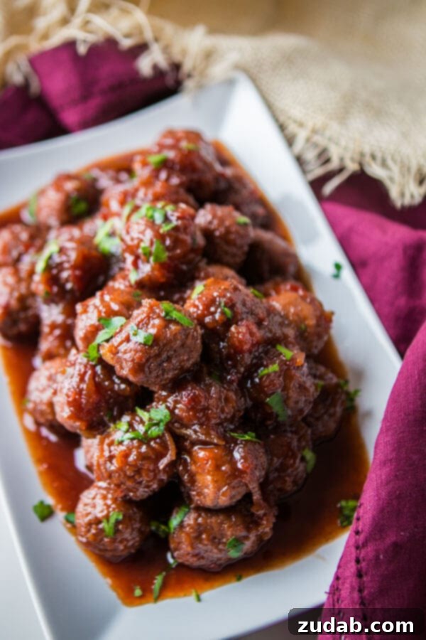 Grape Jelly and Chili Sauce Meatballs served on a white plate with parsley garnish