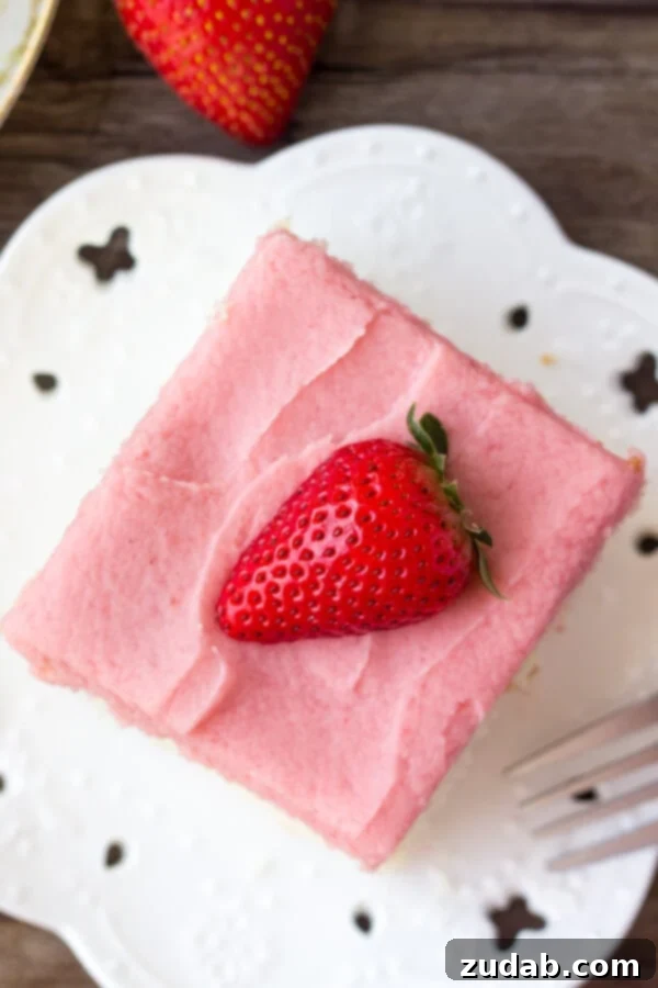 Homemade Strawberry Buttercream Frosting A close-up shot of the stunning pink strawberry buttercream on a vanilla sheet cake, highlighting its creamy texture.