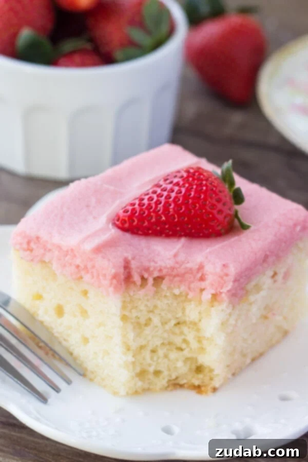 Perfectly Baked Vanilla Cake A beautifully sliced vanilla cake with strawberry buttercream and a fresh strawberry, ready to be enjoyed as a perfect springtime treat.