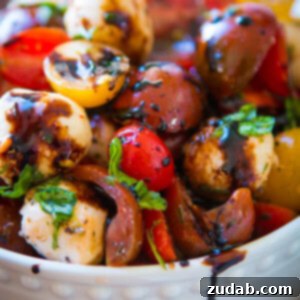 A vibrant, fresh Easy Tomato Mozzarella Salad, drizzled with balsamic glaze and garnished with basil, perfect for a light and delicious meal or side.