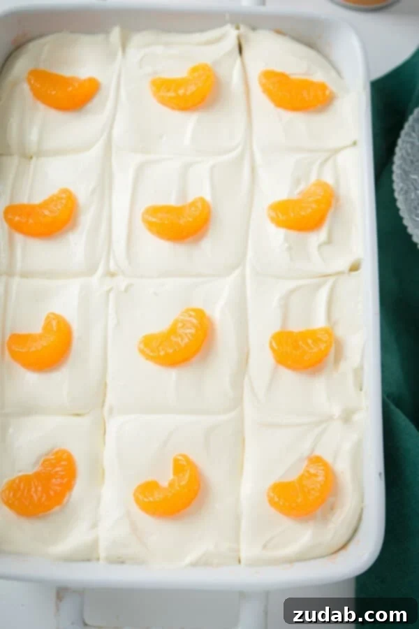 A classic Lemon Mandarin Orange Jello Salad, perfect for holiday meals, featuring a bright orange gelatin base and a creamy lemon topping. mandarin orange jello salad in white baking dish