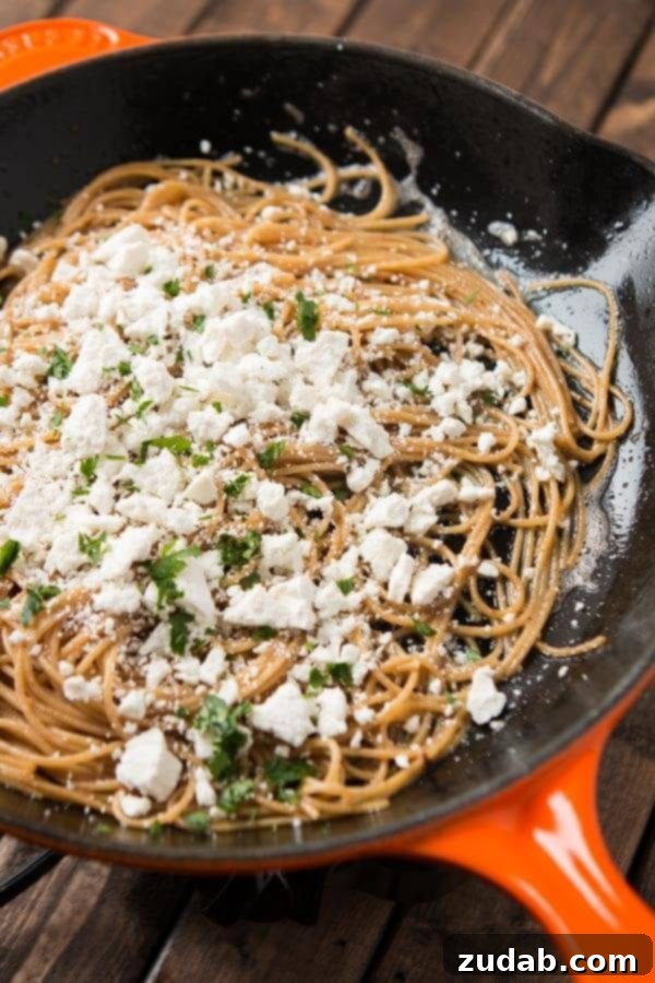A close-up shot of Old Spaghetti Factory Mizithra Cheese and Browned Butter Spaghetti, garnished with fresh parsley. The browned butter coats the pasta, and the crumbly mizithra cheese is visible. ohsweetbasil.com