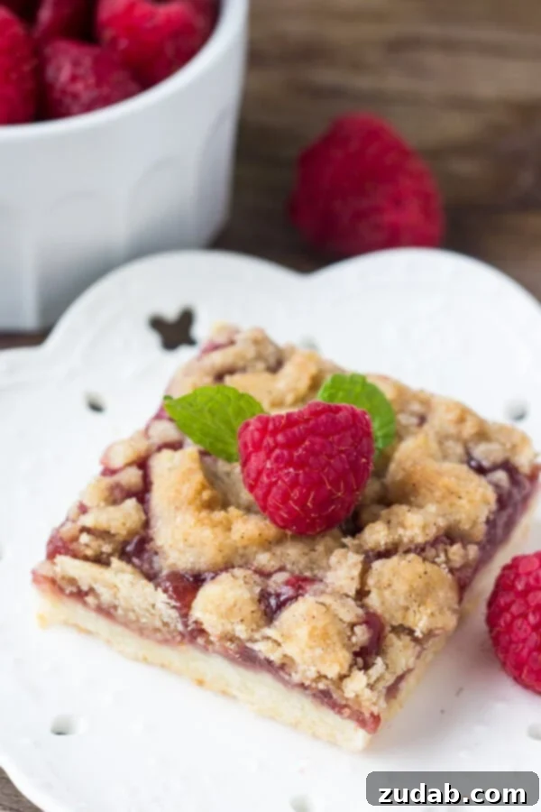 Homemade Raspberry Crumble Bars with Shortbread Base and Glaze Close-up of freshly baked Raspberry Crumble Bars with a golden crust and visible raspberry filling.